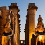 Illuminated statues and columns at Luxor Temple during sunset in Egypt.