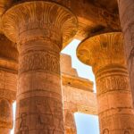 Close-up view of ancient Egyptian temple columns with hieroglyphics under daylight.