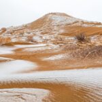 Captivating view of a snow-dusted desert dune under a clear winter sky.