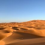 Expansive dunes under a clear blue sky in Egypt's Al Wahat Al Dakhla Desert.