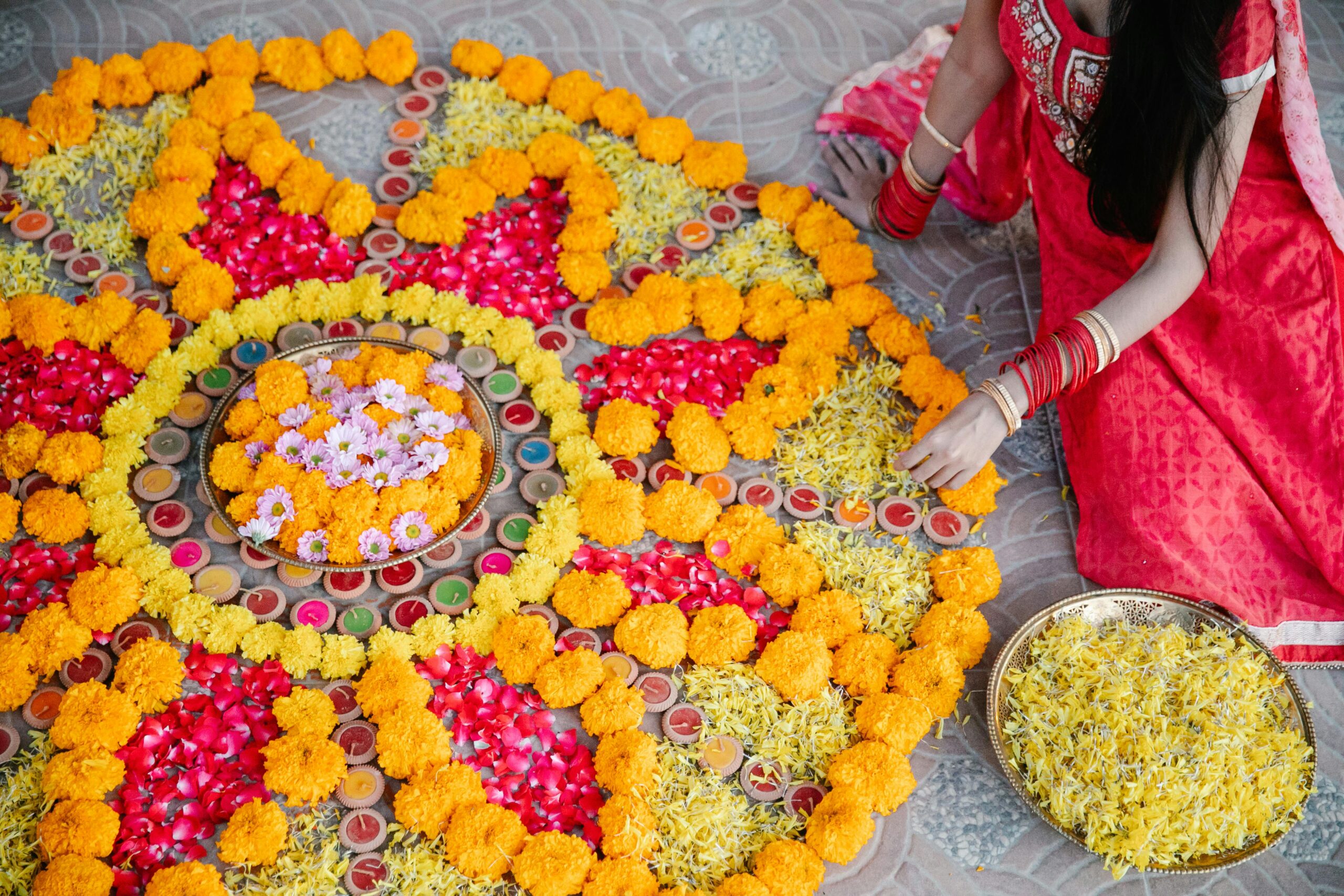 Woman in traditional attire creating colorful rangoli for a festival.